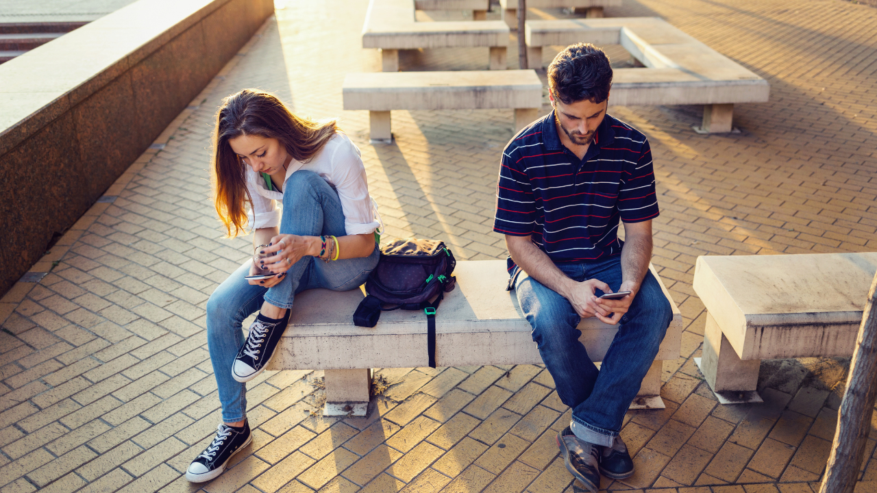 Two people in the same room both looking at their phones, not engaging with each other