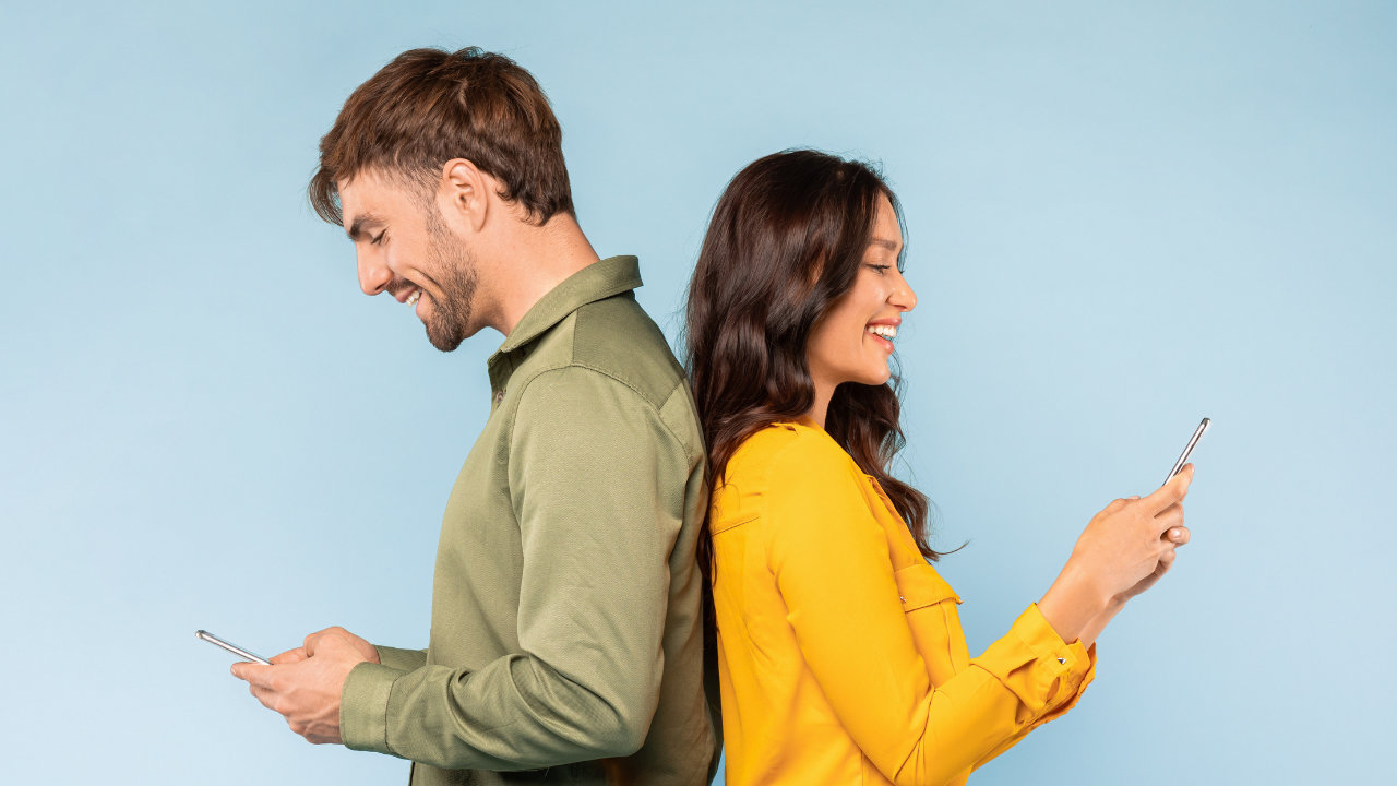 Couple smiling while looking at a phone together, suggesting renewed connection