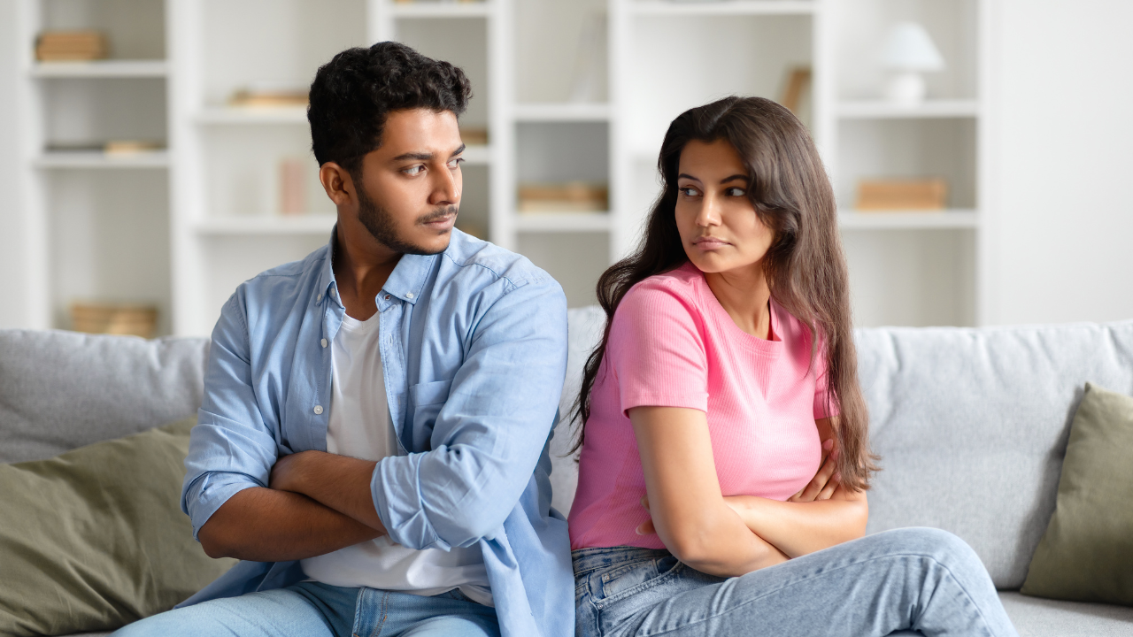 Couple sitting together but looking distant, suggesting emotional disconnect